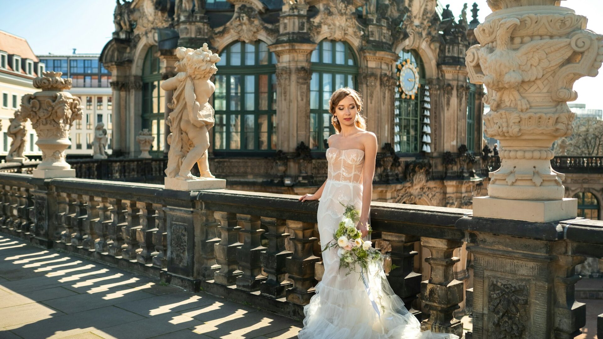 A bride in a white dress with a bouquet on a wedding walk at the famous Baroque Zwinger Palace in