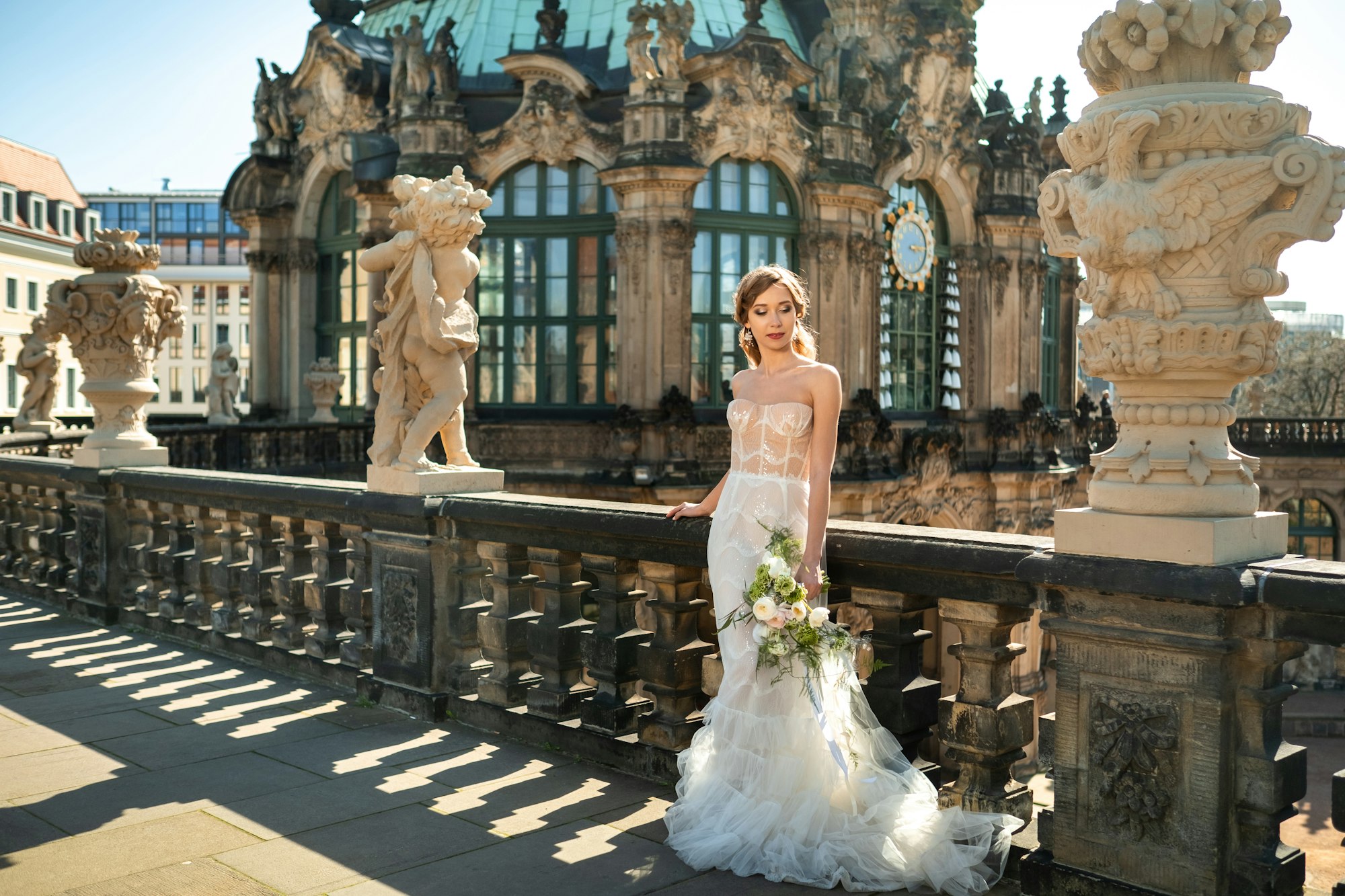 A bride in a white dress with a bouquet on a wedding walk at the famous Baroque Zwinger Palace in